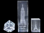 CRISTAIS, lote composto por três (3) blocos decorativos confeccionados em cristal translúcido, com gravações internas representando o Empire State Building, a Torre Eiffel e composição geométrica abstrata, medindo 14,5cm (bicada), 6x4x4cm (bicada) e 6x5x4cm.