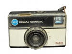 FOTOGRAFIA, uma (1) máquina fotográfica KODAK (tradicional fabricante norte-americana fundada em 1888, amplamente reconhecida pela popularização da fotografia e pela produção de câmeras e filmes ao longo do século XX), modelo 155X, tipo Instamatic, com corpo em material sintético bicolor e flash incorporado. Peça apresentando sinais de uso e do tempo. Sem testes. Sem garantia de funcionamento.