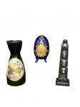 PORCELANAS e ESCULTURA, lote com três (3) peças, sendo: A) 1 garrafa para saque, confeccionada em porcelana na tonalidade preta, decorada por paisagem com pássaro em policromia e filetes em ouro, medindo 13x4cm, B) 1 caixa porta joias no feitio de ovo, confeccionado em porcelana na tonalidade azul, com decoração floral em vasta douração e guarnição em metal dourado, medindo 10x5,5cm e C) 1 escultura totêmica em resina na tonalidade preta, medindo 14cm de altura.