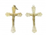 ARTE SACRA, dois (2) crucifixos confeccionados em metal espessurado a prata, ricamente cinzelados por elementos vegetalistas com recortes na borda e inscrição INRI, 1 com leves falhas na prateação, medindo 7,5x5cm.