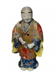 ESCULTURA SATZUMA, uma (1) escultura confeccionada em porcelana oriental na tonalidade branca representando sábio chinês, ricamente decorado por elementos florais e vegetalistas em policromia com realces em ouro e relevo, medindo 27cm de altura, mão colada, assinado no fundo.