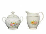 PORCELANA REAL, duas (2) peças, sendo: A) 1 açucareiro, medindo 10x12,5x7cm e B) 1 leiteira, medindo 10,5x10,5x5cm, confeccionadas em porcelana na tonalidade branca, com pintura de elementos florais em policromia e filetes em ouro.