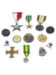MILITARIA, treze (13) peças, entre medalhas, condecorações, distintivos e insígnias militares, em metal de diferentes formatos, incluindo estrelas, cruzes, botões e emblemas, algumas com fitas nas cores vermelho e branco, verde e amarelo, e roxo e dourado. Lote apresentando sinais do tempo, maior 4cm e menor 2x2,5cm.