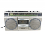SOM, um (1) rádio gravador cassete da marca NATIONAL (tradicional fabricante japonesa ligada ao grupo Matsushita/Panasonic, reconhecida pela produção de aparelhos eletrônicos de uso doméstico), modelo RX-495FA, 4-BAND STEREO RADIO CASSETTE RECORDER, com recepção FM, MW, SW1 e SW2, gabinete em plástico nas cores prata e preto, alça superior, controles superiores e compartimento frontal para fita cassete, apresentando sinais de uso, marcas do tempo e desgaste no acabamento, ligando, sem garantia de funcionamento, medindo 22x43x10cm.