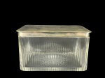 CRISTAL EUROPEU, uma (1) caixa porta joias, confeccionada em cristal europeu translucido com lapidação de caneluras em baixo relevo, fundo estrelado e tampa em metal espessurado a prata, medindo 9x16x12cm.