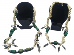 BIJUTERIAS, dois (2) colares em cordão trançado de tom bege, adornado com contas verdes em madeira pintada e arremates plásticos imitando metal prateado, com pingentes pendentes no mesmo padrão decorativo, medindo 40cm e 50cm.