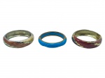 BIJUTERIAS, lote com três (3) braceletes de modelos distintos, sendo: A) 2 em metal dourado com esmaltagem policromada e elementos geométricos em relevo, sinais de uso, medindo 6,5cm de diâmetro e B) 1 em metal prateado com incrustação em material sintético na tonalidade azul imitando pedra, apresenta oxidações, sinais de uso, medindo 7cm.