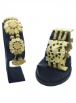 JOIAS, dois (2) braceletes confeccionados em MARFIM entalhado a mão, sendo: A) 1 com monture elástica, contas esféricas e representando flor, sinais de puído na monture, medindo 7cm e B) 1 decorada por placas vazadas em elementos geométricos e centro em elefante, medindo 17cm de comprimento.