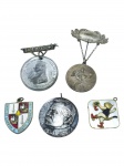 MEDALHAS, cinco (5) peças em metal prateado e dourado, sendo medalhas e distintivos comemorativos, alusivos a efígie da Rainha Vitória, cena esportiva, brasão do Bank of London & South America, medalha com busto de David Pomeroy e peça esmaltada com figura de felino. Apresentando sinais do tempo, maior medindo 4cm e menor 2,5x2,5cm.