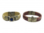 BIJUTERIAS, lote com dois (2) braceletes, confeccionados em osso com guarnições metálicas, sendo: A) um claro com incrustação de lápis-lazúli e ausência do pino do fecho, medindo 7x5,5cm e B) um com pintura vermelhada e frisos escurecidos, cinzelado floral na guarnição, medindo 7x6,5cm.