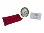 RELÓGIO, m (1) relógio de mesa da marca Cartier (tradicional maison francesa fundada em 1847, reconhecida mundialmente por sua produção de joias, relógios e objetos de luxo de alto padrão), confeccionada em metal dourado, caixa ovalada, mostrador branco com algarismos romanos, verso com numeração 890804307, acompanhado de estojo em veludo vermelho da marca e cartão Cartier International Service. Peça apresentando sinais do tempo e do uso, sinais de oxidação e 1 bilro traseiro solto. Não testado e sem garantia de funcionamento. No estado, medindo 9x7cm.