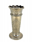 METAL PRATEADO / HERRMANN = Um (1) vaso floreiro em metal prateado, de formato cilíndrico, com borda ondulada, bojo ricamente ornamentado com motivos florais e arabescos em relevo, frisos decorativos e base circular alargada. Medida :  26 x 11 cm