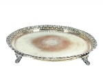 METAL PRATEADO / REBOUÇAS - (1) Bandeja de formato circular confeccionada em  metal espessurado à prata , com centro liso, galeria vazada em desenho ornamental e apoio sobre pés recortados , ausência de um pé e necessita de banho , medida : 37 cm