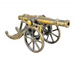 MILITARIA - Um (1) canhão decorativo em bronze, com tubo cilíndrico montado sobre reparo com rodas raiadas, apresentando inscrição SCAFLAM. Medida : 17 x 23 x 10 cm