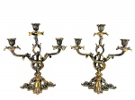 BRONZE - Um par de candelabros para três velas, em bronze,  braços recurvados, haste central vazada, bocais em forma de flor e bases recortadas, ricamente ornados com volutas, folhagens e elementos vazados. Medida : 31 x 29 cm