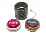 COLECIONISMO, três (3) peças, sendo: A) uma (1) mola maluca em metal; B) um (1) ioiô publicitário da COCA-COLA, modelo Super, em material plástico; e C) um (1) ioiô publicitário da COCA-COLA, modelo Galaxy, em material plástico com corpo translúcido e glitter. Peças apresentando sinais do tempo e uso, medindo 5,5cm.