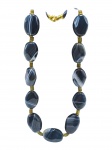 BIJUTERIA, um (1) colar, com contas em ágata, em formato oval e irregular, em tonalidade escura com faixas naturais esbranquiçadas, intercaladas por espaçadores cilíndricos em metal dourado e missangas, medindo 48cm de comprimento.