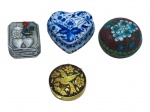 DIVERSOS, quatro (4) caixinhas porta pílulas de modelos, tamanhos, decorações e materiais distintos, sendo: A) 1 em porcelana no formato de coração com pintura floral em monocromia na tonalidade azul, medindo 5x5cm, B) 1 confeccionada em metal espessurado a prata de origem portuguesa, decorada por Galo de Barcelos em policromia, medindo 3,5x3cm, C) 1 confeccionada em metal dourado de Toledo, decorado por pássaro e elementos florais, medindo 3,5cm e D) 1 confeccionada em cloisonné com pintura floral sobre fundo vermelho, medindo 3x4cm.