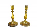 BRONZE, par (2) de castiçais, confeccionadas em bronze com vestígios de banho de prata, corpo balaustre, apoiado sobre base circular escalonada, 1 com mossa no corpo, medindo 17cm de altura.