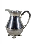 METAL PRATEADO, uma (1) jarra, confeccionada em metal espessurado a prata, bojo liso com friso horizontal em relevo, apoiada sobre 3 pés concheados e aparador de gelo vazado, alça cinzelada em folhagens, medindo 16,5x16x9,5cm.