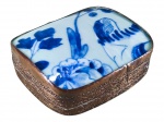 PORCELANA ORIENTAL, uma (1) caixa oriental, confeccionada em metal cobreado, cinzelado por guirlanda floral e tampo com incrustação de placa em porcelana na tonalidade branca com elementos florais na técnica BLUE and WHITE, mossas no metal, medindo 4,5x12x11cm.