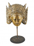 ESCULTURA, uma (1) máscara decorativa de inspiração oriental, confeccionado em bronze, representando Deusa Tara (é uma das divindades mais importantes e amadas do Budismo Tibetano (Vajrayana), representando a compaixão ativa, a sabedoria desperta e a energia feminina dos Budas), com elaborado diadema rendilhado, apoiada sobre haste removível e base circular com cinzelado de folhagens, medindo 35x20cm.