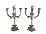 METAL PRATEADO, par (2) de candelabros para 5 velas confeccionados em metal espessurado a prata, hastes curvas no feitio de arabesco, corpo cônico encimado por esfera, apoiada sobre base oval em recortes com rico cinzelado de elementos vegetalistas relevados, necessita banho novo, medindo 44cm de altura.