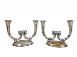 METAL PRATEADO, par (2) de candelabros para duas velas da manufatura EBERLE, confeccionado em metal espessurado a prata, hastes curvas no feitio de arabesco com esfera central, apoiada sobre base oval e escalonada, apresentando falhas no banho, medindo 20x24,5cm.