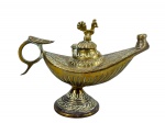 BRONZE, uma (1) lamparina confeccionada em bronze, ao gosto oriental, modelada no formato navicular, com tampa articulada encimada por figura de galo, bico alongado, cabo vazado e base circular. Peça com cinzelados geométricos, medindo 10x13,5cm.