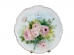 PORCELANA, um (1) prato decorativo confeccionado em porcelana na tonalidade branca, com pintura de flores e folhagens em policromia, assinado GUIDA, borda em recortes, filetados em ouro, medindo 27cm.