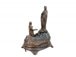 ARTE SACRA, um (1) grupo escultórico em metal cobreado, representando a aparição de Nossa Senhora de Lourdes, com figura da Virgem sobre rochedo e vidente ajoelhada, sobre base circular com inscrição alusiva, medindo 15,5x12x8cm.
