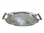 METAL PRATEADO, uma (1) bandeja oval confeccionada em metal espessurado a prata, cinzelado por caneluras, fitas torcida e elementos florais , alças em vazados com cabo torneado, medindo 54x30cm.