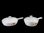 PYREX CORNING (AMERICANO), duas (2) panelas confeccionadas em vidro temperado na tonalidade branca, decorado por flores e folhagens em policromia e tampa translucida, maior medindo 8,5x26x17,5cm e menor 9,5x24x15cm.