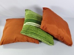 Três almofadas com capas, laranjas e verde