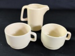 Conjunto com três peças de porcelana/ cerâmica, sendo uma jarra leiteira e duas xícaras.