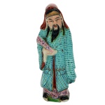 Estatueta em porcelana chinesa policromada, representando Imortal taoísta com atributo na mão direita. Base recortada. 10 x 4 x 3 cm.