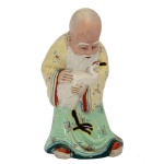 Estatueta em porcelana chinesa policromada representando Shou Xing, o Deus da Longevidade, segurando a garça Gru, símbolo de longa vida. Base recortada. 12 x 7 x 5 cm.