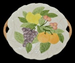 Prato para bolo em porcelana da manufatura italiana, moldada com frutos em relevos, rematados em policromia de esmaltes. Itália. Década de 1970/80. 33 cm.