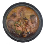 Medalhão, possivelmente holandês, em cerâmica moldada em alto relvo e esmaltada, ornamentando por cena de taberna com casal. Borda e fundo de cor chumbo. 34 cm.