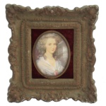 Miniatura oval, pintada em policromia, representando busto de jovem mulher. Moldura ondulada e rematada por quinas salientes de ferro. 8 x 6 cm (MI). 18 x 17 cm (ME).