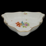 HEREND  Elegante travessa de forma triangular em porcelana húngara, ornamentada em policromia floral e filetes a ouro. Marcas da manufatura sob as bases. 5 x 26 x 24 cm.