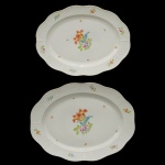 HEREND  Elegante conjunto de duas travessas de forma oval em porcelana húngara, ornamentada em policromia floral e filetes a ouro. Marcas da manufatura sob as bases 37 x 28 cm e 42 x 32 cm.