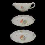 HEREND  Elegante conjunto de molheira de forma navicular e 2 covilhetes de forma oval em porcelana húngara, ornamentada em policromia floral e filetes a ouro. Marcas da manufatura sob as bases. 3 x 12 x 17 cm / 3 x 20 x 15 cm (covilhetes). 9 x 8 cm (molheira).