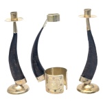 Conjunto de 3 peças montadas com chifres escuros e metal dourado. Apresentam um par de castiçais com bases e bobeches metálicas, e porta garrafa de mesmo tipo com base larga em metal dourada ornado por friso com florões. 25 x 7 cm (par de castiçais). 24 x 13 cm (porta garrafa).