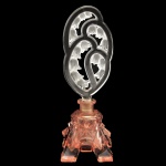 Elegante perfumeiro em cristal com bojo de cor salmão moldado no formato de pedra facetada. Original e delicada tampa transparente, acetinada e vazada, moldada com galhos recurvos e floridos com lírios-do-vale. 22 x 7 x 7 cm.