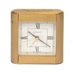 TIFFANY & Co. - Relógio de mesa (desk clock). Caixa em metal com acabamento dourado. Numerais romano, mostrador com textura central e a inscrição personalizada Mont and Leonard, November, 17,1990 no topo da caixa. 10 x 10 x 3 cm.