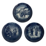 Belíssimo conjunto de 3 pratos Royal Copenhagen  série Natal (1980, 1981 e 1985) - Conjunto composto por três pratos em porcelana dinamarquesa da renomada manufatura Royal Copenhagen, pertencentes à tradicional série anual de Natal. Decorados em azul cobalto sob esmalte, apresentam cenas natalinas delicadamente executadas, correspondentes aos anos de 1980, 1981 e 1985. Peças de reconhecida qualidade e tradição, amplamente colecionadas internacionalmente. 18 cm