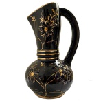 Jarra em cerâmica artística Da Costa, azul cobalto com detalhes em ouro, 1957 - Elegante jarra decorativa em cerâmica artística brasileira da manufatura Da Costa, São Caetano do Sul (SP), apresentando intenso azul cobalto com rica decoração floral aplicada à mão em ouro. Peça assinada, datada de 1957 e acompanhada de etiqueta original de fábrica, cerâmica artística brasileira do período. Apresenta forma elegante com alça robusta e acabamento de alta qualidade.