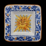 DOLCE & GABBANA  Covilhete de formato quadrangular em cerâmica artesanal italiana e decorativa com motivos solares vibrantes ao centro. Borda decorada com padrões florais azuis e amarelo. 3 x 16 x 16 cm.