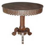 Mesa de apresentação em madeira nobre, com tampo circular liso. Borda sustentando placas retangulares acopladas, recortadas em arcos e vazadas nas extremidades. Coluna central facetada, apoiada em base quadrangular sobre pequeno plateau ladeado por largas pernas em S, reunidas por friso inferior. 82 x 92 cm.